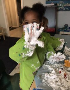 Little Laurelhurst Preschool - Creative Art - Child Holding Up Their Hand Covered in Shaving Cream and Paint